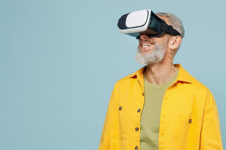 Vanhempi mies keltaisessa paidassaan tutustuu virtuaalilaseilla VR-ympäristöön.